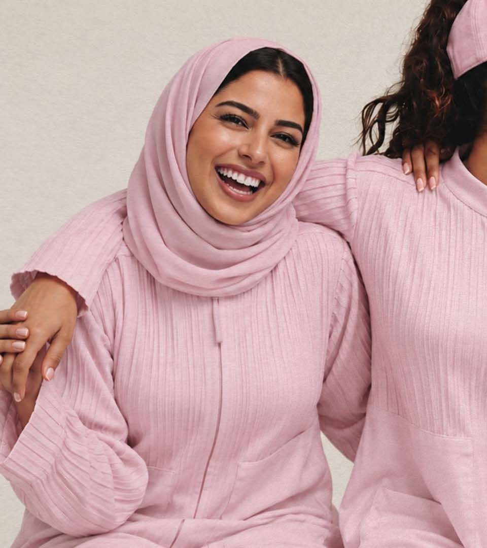 Three women in pink DAS sports abayas smiling together